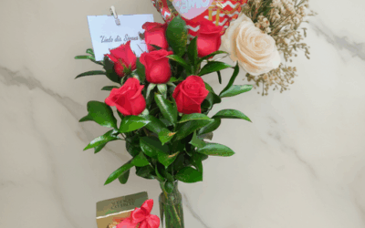Arreglo de rosas rojas en florero de vidrio con globo de corazón que dice te amo, rosa clara y caja de chocolates Ferrero Rocher sobre fondo de mármol claro