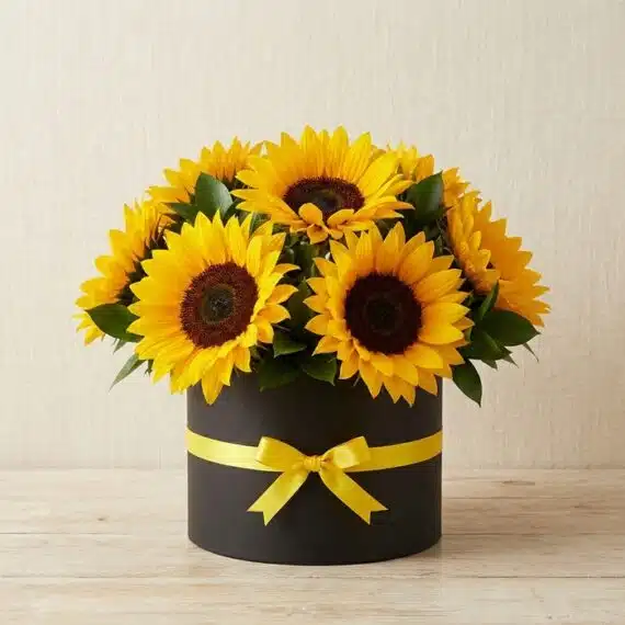 Arreglo floral de girasoles MARISA en caja negra con lazo amarillo, ideal para ecommerce de floristería, con fondo elegante e