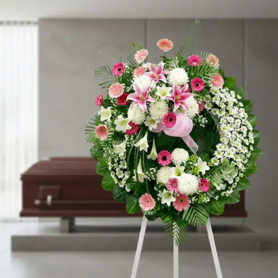 Corona fúnebre solemne 'Homenaje a Mathias' con flores blancas, rosas y follaje verde, en una sala de velación moderna con at